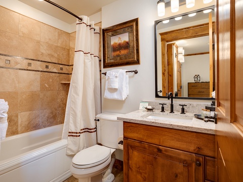 Unwind in your private bathroom with a soaking tub, warm tile surround, and fresh linens waiting for you. The rustic wood vanity and elegant fixtures create a cozy, inviting space to refresh after mountain adventures.
