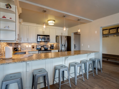 Gather around this spacious kitchen island where granite countertops and pendant lighting set the stage for your vacation meals. Modern appliances and a tiled backsplash make cooking effortless.