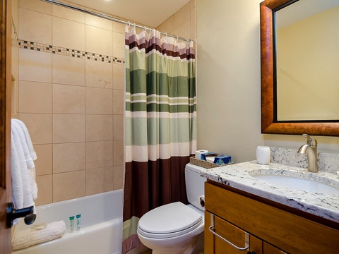 Your private bathroom features warm wood accents, a deep soaking tub, and fresh towels ready for your arrival—a perfect retreat after exploring the area.