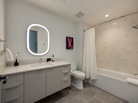 Step into your sleek, modern bathroom with a glowing backlit mirror, spacious vanity, and pristine tub-shower combo—perfectly designed for your comfort and relaxation.