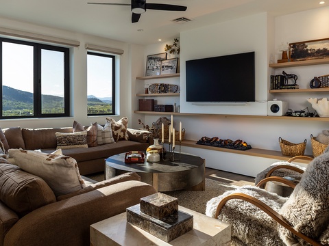 Sink into plush seating and soak in stunning mountain vistas through floor-to-ceiling windows. Your cozy retreat features a stylish fireplace, smart TV, and warm textures that invite you to unwind in comfort.
