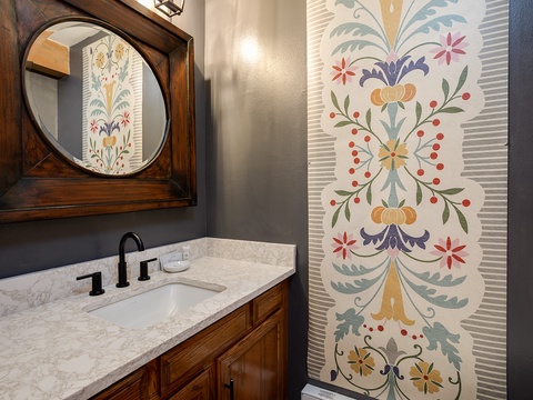 Step into this charming bathroom where rich wood tones meet artistic flair. The stunning hand-painted floral mural adds a whimsical, personal touch to your private retreat.