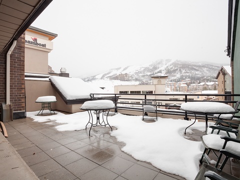Snow-dusted terrace offering serene mountain views in the heart of a premier ski resort destination with easy access to slopes and village amenities.