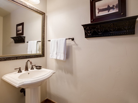 Freshen up in your elegantly appointed bathroom with classic pedestal sink, framed mirror, and plush towels. The charming décor adds a touch of vintage character to your stay.