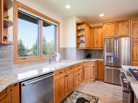 Your gourmet kitchen features custom cabinetry, granite counters, and premium appliances. Large windows frame scenic views while you prepare meals, and open shelving displays charming local touches. Everything you need for a memorable stay awaits.