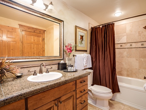 Unwind in this warm bathroom featuring granite counters, a walk-in shower with tile detail, and fresh towels ready for your comfort.