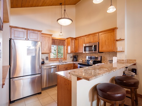 Your fully equipped kitchen features granite countertops, stainless steel appliances, and a breakfast bar—perfect for preparing meals and gathering with loved ones in this warm, inviting space.