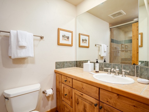 Refresh in your private bathroom with warm wood accents, a spacious tiled shower, and plush towels ready for your arrival.