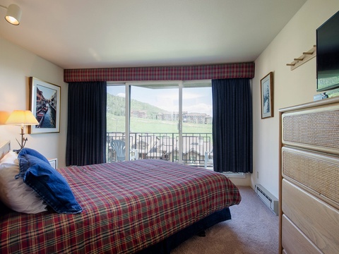 Wake up to stunning mountain vistas from your cozy bedroom, where plaid accents and comfortable furnishings create a welcoming alpine retreat.