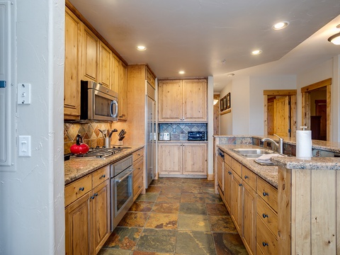 Your spacious kitchen features warm wood cabinetry, granite counters, and modern stainless appliances—perfect for preparing meals during your mountain getaway.