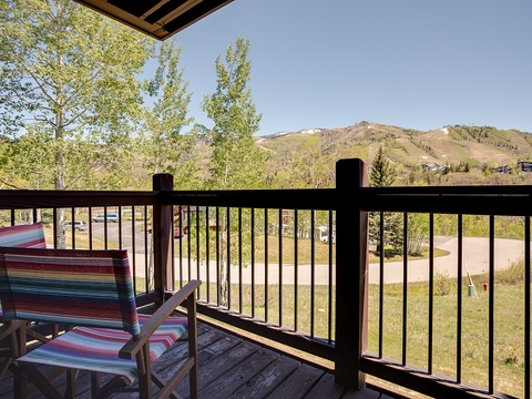 A covered balcony overlooks rolling hillsides and lush green surroundings, offering a peaceful retreat for morning coffee or evening relaxation.