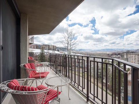 Private balcony featuring two cushioned chairs and a bistro table, offering expansive mountain views and a refreshing outdoor retreat during your stay.