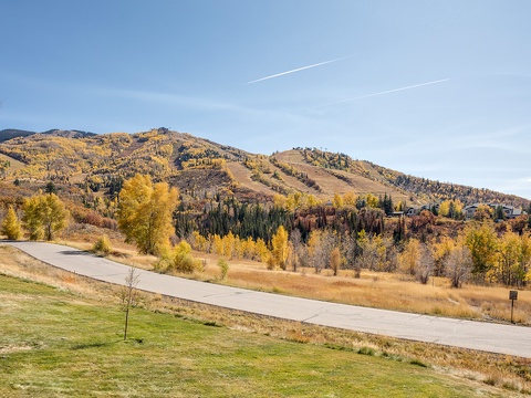 A picturesque mountain setting with vibrant autumn foliage blanketing the slopes, offering scenic walking paths through golden aspen groves and evergreen forests.