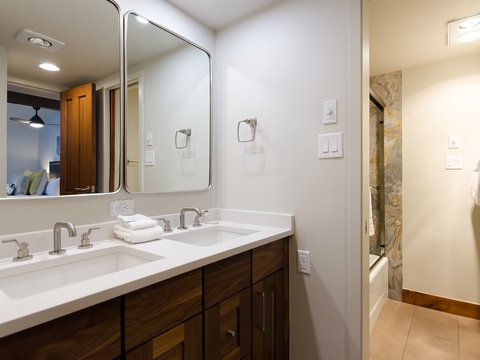 Unwind in your private bathroom featuring dual vanities, elegant marble counters, and a spacious walk-in shower with natural stone tile for a spa-like retreat.