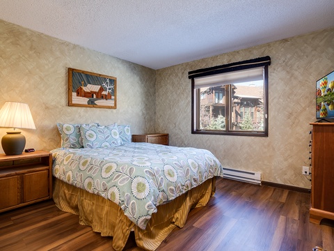 Sink into a plush queen bed adorned with cheerful linens while warm lamplight and charming artwork welcome you. Your private retreat features rich wood floors, entertainment, and a peek of mountain views from your window.