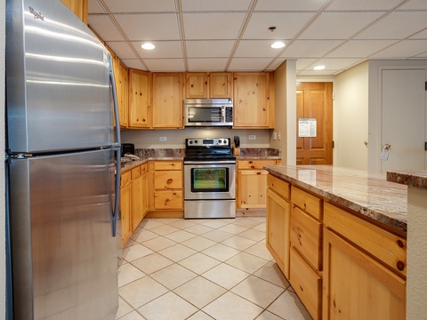 Your fully equipped kitchen features stainless steel appliances, warm wood cabinetry, and ample counter space—perfect for preparing family meals or morning coffee during your stay.