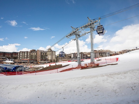 Ski resort gondola servicing snowy slopes, with lodging and facilities visible at the base during winter season.