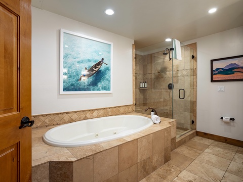 Unwind in your private spa-like bathroom with a jetted soaking tub and spacious walk-in shower. Warm tile and art-filled walls create a serene escape after a day of adventure.