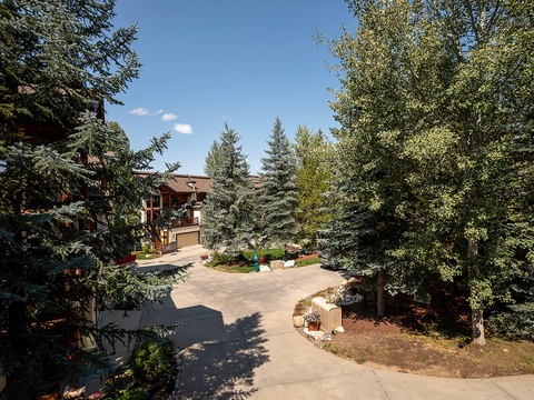 A welcoming mountain retreat surrounded by mature evergreens and aspen trees, with private driveway and garage access in a serene natural setting.