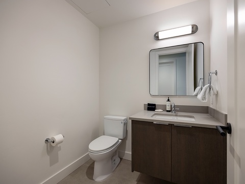 Your modern bathroom features clean lines, a sleek vanity, and fresh towels ready for your arrival—simple, stylish comfort.