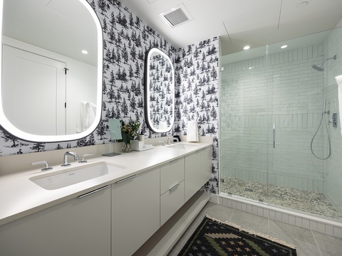 Step into your sleek, spa-inspired bathroom with a spacious walk-in shower, elegant vanity, and charming woodland-patterned wallpaper that adds a touch of whimsy to your mountain escape.