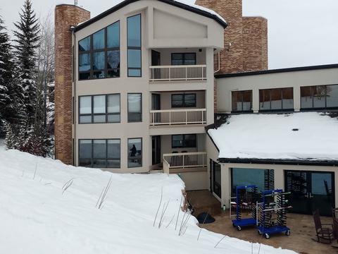 A multi-story slope-side building nestled in a snowy mountain setting, offering convenient ski-in access during the winter season.