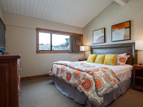 Settle into your cozy bedroom with vibrant linens, warm lighting, and a peaceful vaulted ceiling—your restful retreat after a day of exploring.