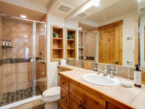 Freshen up in your private bathroom with a walk-in shower, stylish tile accents, and warm wood cabinetry. The recessed lighting and spacious vanity create a relaxing retreat after your adventures.