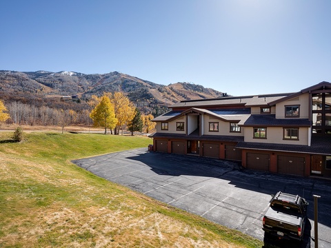 Spacious mountain property framed by autumn foliage and ski slopes, offering expansive grounds, multiple garages, and scenic surroundings perfect for year-round getaways.