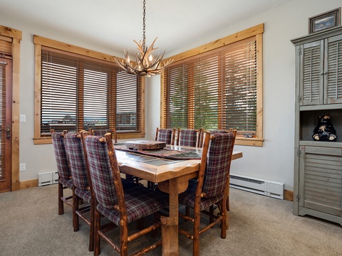 Gather around this inviting dining table, where rustic charm meets comfort. Natural light pours through warm wood-framed windows, creating the perfect setting for your mountain meals together.