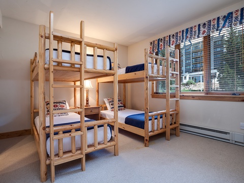 This cozy room sleeps four with sturdy wooden bunk beds dressed in crisp linens and cheerful accents, perfect for family getaways or group adventures.