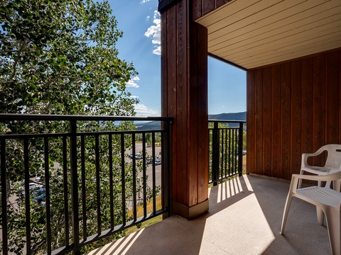 A private balcony framing peaceful tree-lined views and distant hills, perfect for savoring your morning coffee in the fresh mountain air.