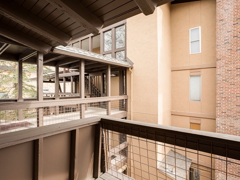 Modern multi-level architecture with exposed beams, metal railings, and varied textures creating an urban industrial aesthetic at the property entrance.