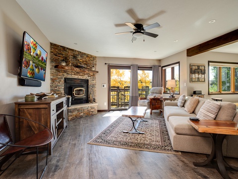 Sink into the plush sofa by the stone fireplace, enjoy autumn views from your private balcony, and unwind with your favorite show on the wall-mounted TV—your perfect mountain retreat awaits.