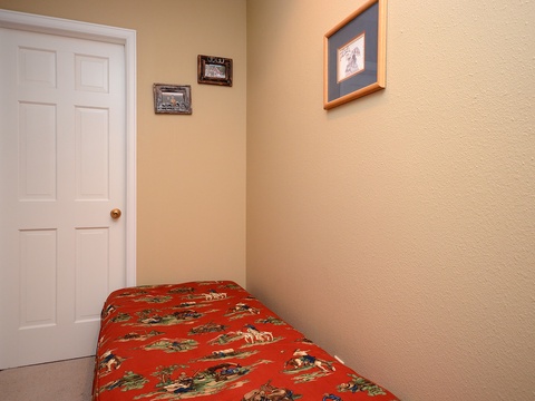 Your cozy sleeping nook features a vibrant western-themed bed, warm peach walls adorned with charming artwork, and a private door for added comfort and convenience.