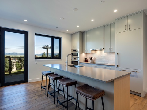 Step into your sleek, modern kitchen with mountain views framing every meal. The spacious island invites you to gather and create, while natural light pours through glass doors leading to your private outdoor space.