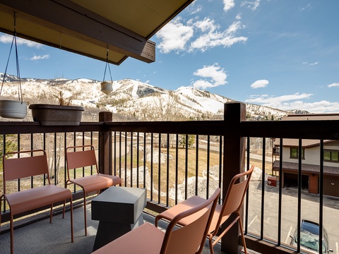 Stunning mountain panorama from a private balcony with comfortable seating, perfect for morning coffee or après-ski relaxation overlooking snow-dusted peaks and surrounding neighborhood.