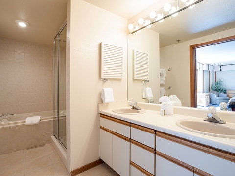 Your spacious bathroom features dual sinks, ample counter space, and a glass-enclosed tub-shower combo. Fresh towels await, with calming neutral tones creating a spa-like retreat.