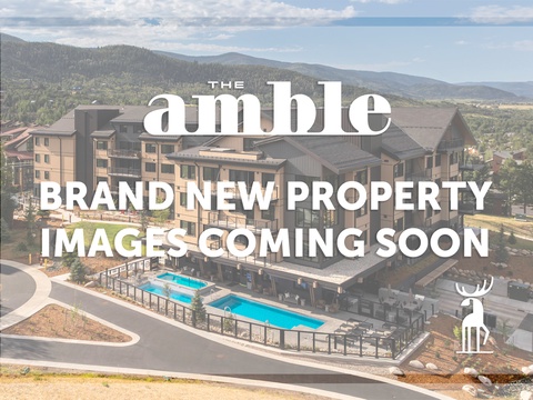 A modern mountain resort property nestled among forested hills, featuring contemporary multi-story buildings, a swimming pool, and surrounded by natural landscape.