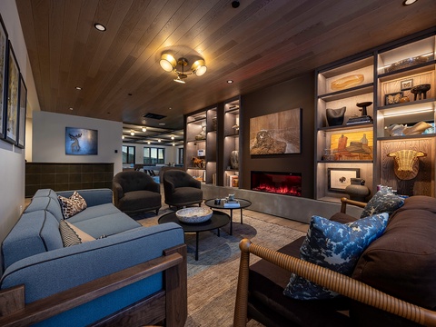 Sink into plush seating around the fireplace, where warm woods and curated shelves create your perfect retreat for evening conversation or quiet reading.