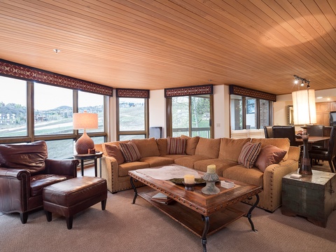 Unwind in your spacious living area with plush seating, warm wood tones, and expansive windows framing scenic mountain views—your perfect retreat after a day of adventure.