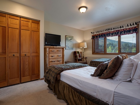 Sink into your plush bed surrounded by warm wood tones and mountain views filtering through the windows. Your cozy retreat features ample closet space and rustic charm.