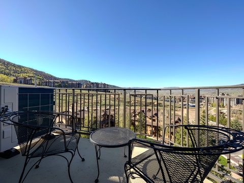 Expansive mountain and valley vistas from the private balcony where outdoor seating awaits clear blue skies and fresh mountain air for morning coffee or evening relaxation.
