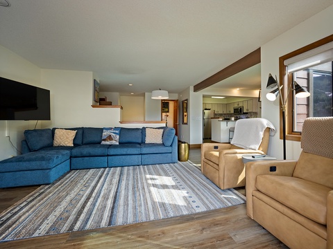 Sink into the plush blue sectional and unwind in this bright, open living space where mountain views greet you through large windows. The fully equipped kitchen beckons just beyond.