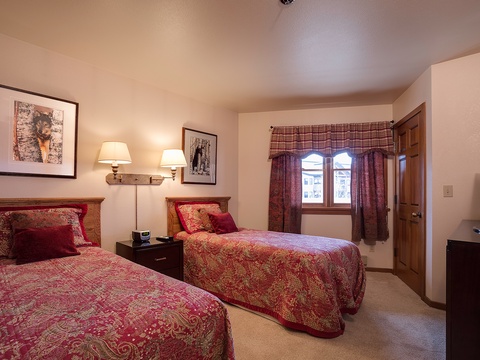 Drift off in comfortable twin beds dressed in rich burgundy linens, illuminated by warm bedside lighting. Cozy up in this thoughtfully designed bedroom that invites restful sleep.