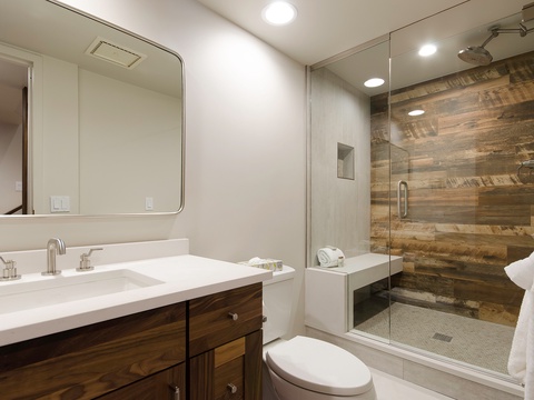 Step into your private retreat: a sleek bathroom featuring a spacious walk-in shower with stunning wood-paneled walls, plush towels, and elegant modern fixtures designed for your comfort.