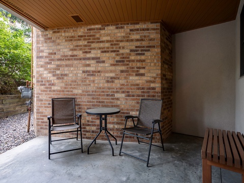 Settle into your private covered patio, where warm wood tones and brick create a peaceful retreat for morning coffee or evening relaxation overlooking the garden.