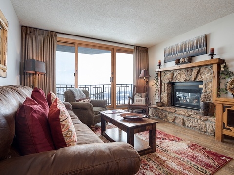 Cozy up in this inviting living room where a stone fireplace anchors the space. Sink into plush seating, enjoy mountain views through expansive windows, and unwind in a warm alpine atmosphere.