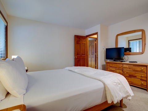 Drift off to sleep in your serene bedroom, where crisp white linens, warm wood accents, and natural light create your peaceful retreat after a day of adventure.