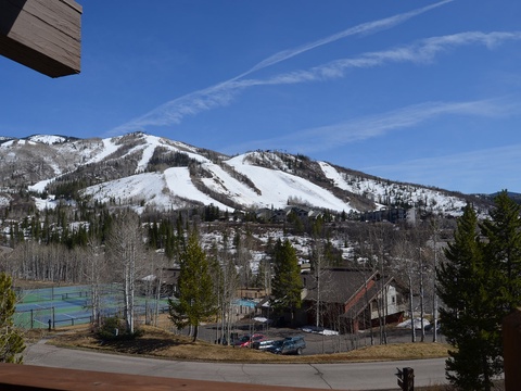 Snow-covered ski slopes frame this mountain resort nestled in a scenic valley, with tennis courts and lodges visible among aspens and pines—a scenic backdrop for your alpine getaway.